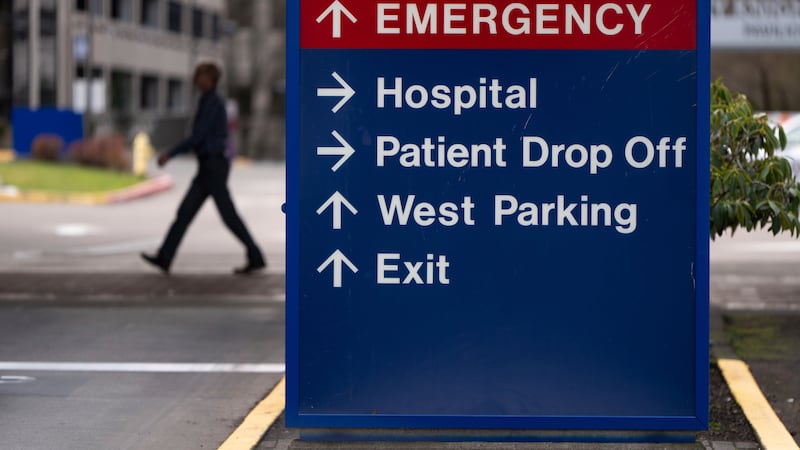 A person walks past a sign directing vehicles towards the emergency room at Providence St....